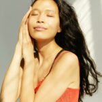 A serene studio portrait of a young woman in a red dress, eyes closed, relaxed pose.